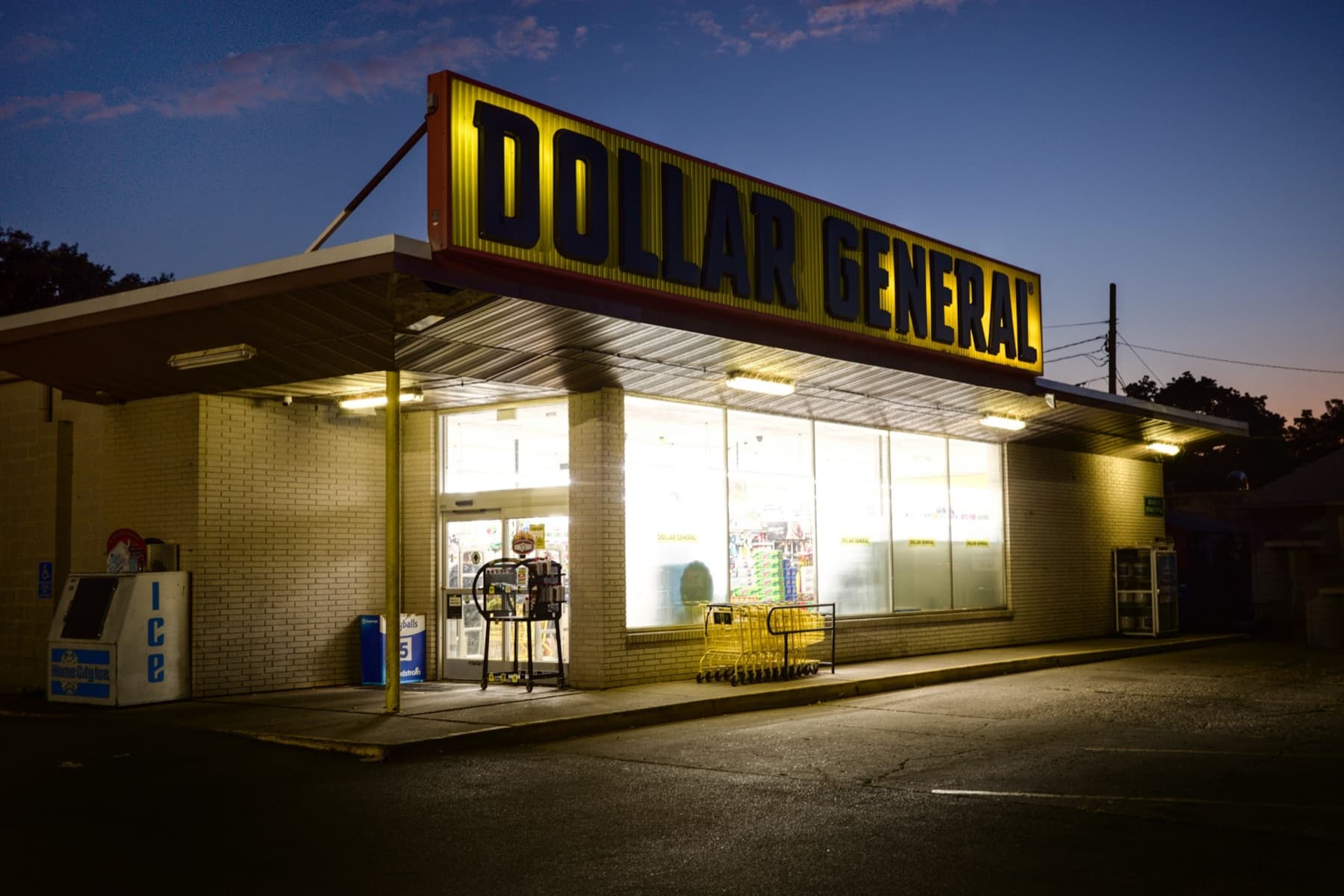 A free-standing Dollar General store lit up at dusk over an empty parking lot