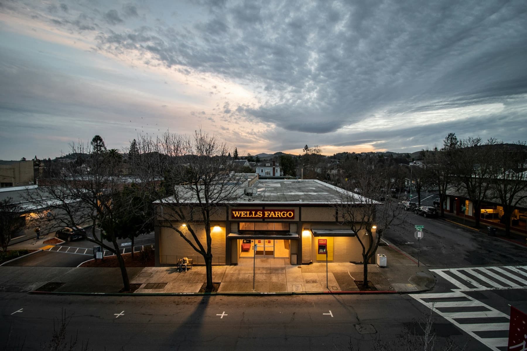 A free-standing bank branch and its parking lot at dusk