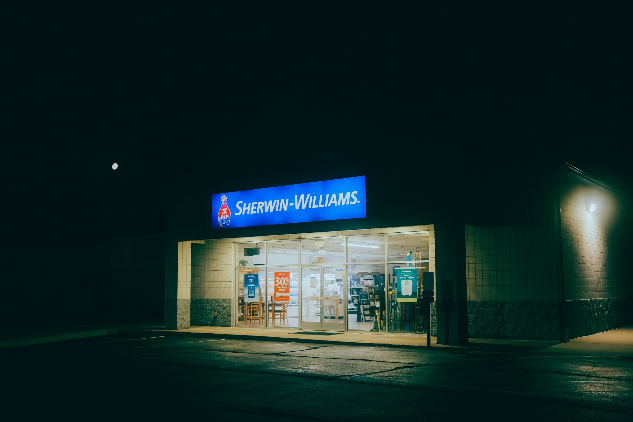 A Sherwin-Williams paint store lit up at night
